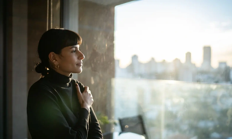 Woman by a sunlit window during the wait after embryo transfer -sv.