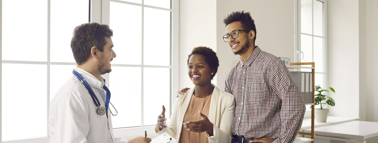 Young couple discussing fertility treatment and IVF medications with their doctor.
