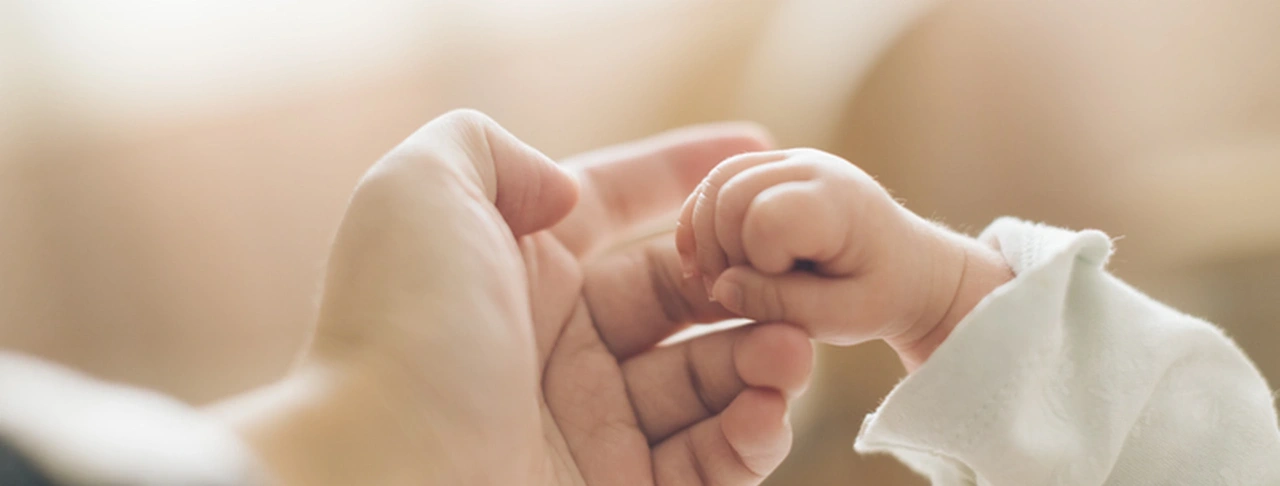 Baby’s hand holding an adult’s thumb.