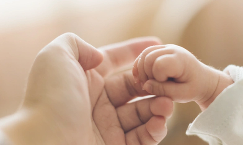 Baby’s hand holding an adult’s thumb.