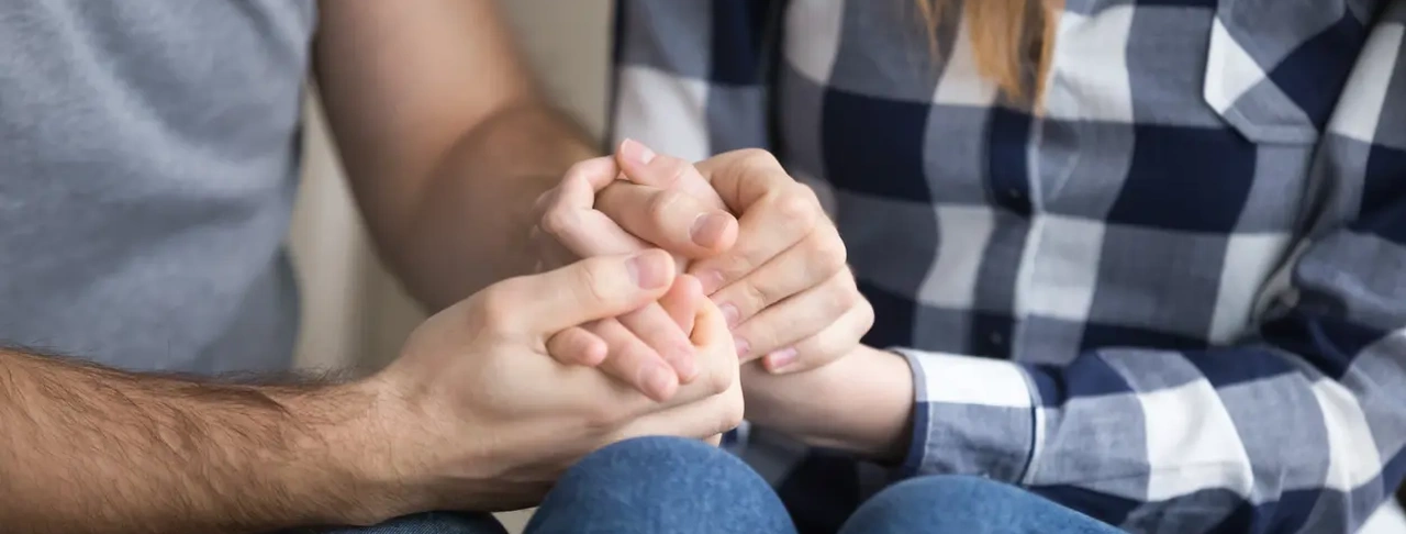 Par som håller varandra i händerna som stöd inför fertilitetsbehandling med donerade ägg eller spermier