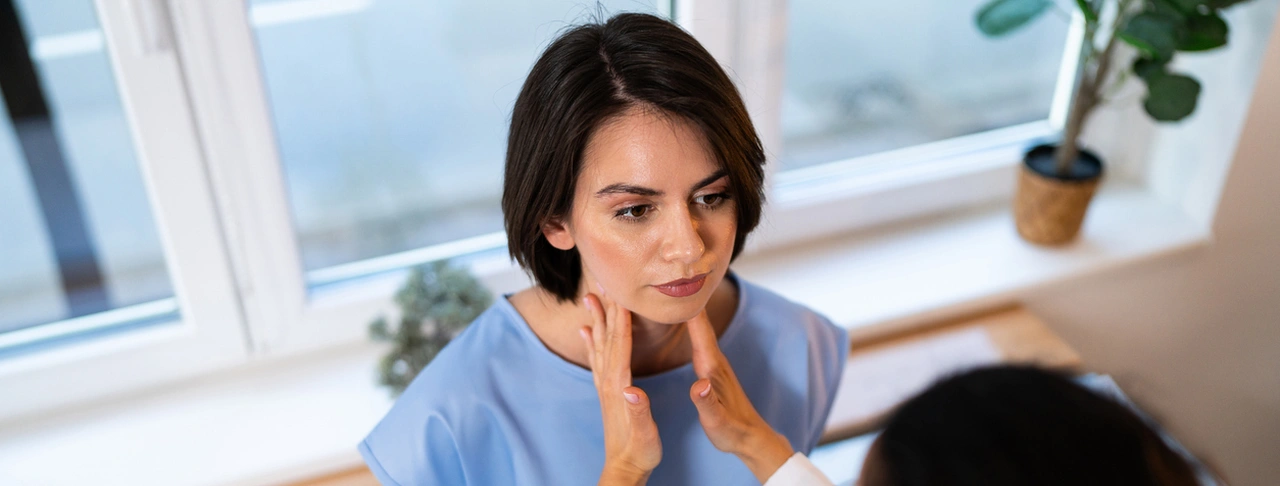 Doctor examining a female patient’s thyroid gland.